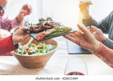 Senior people having italian vegan vegetarian lunch at home - Mature friends eating bbq vegetables,fresh salads and toasting red wine - Healthy concept - Focus on courgette bottom dish - Warm filter  - Powered by Shutterstock