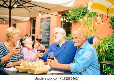 Senior people laughing and toasting red wine at restaurant  - Friendship concept with happy mature friends having fun together at home in the garden