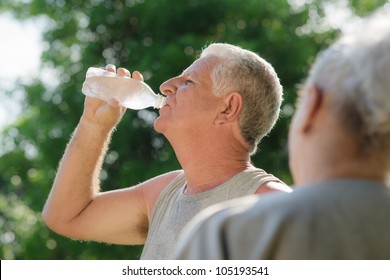 Senior People, Old Man And Woman Talking And Drinking Water After Exercising In Park