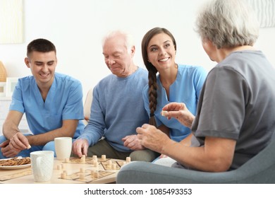 Senior People Playing Bingo With Their Caregivers Indoors