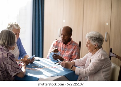 Senior People Playing Cards At Table In Retirement Home