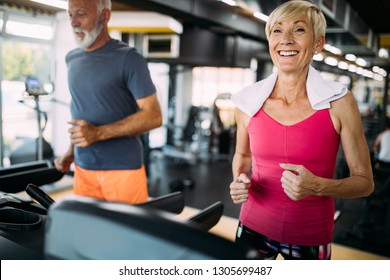 Senior People Running On A Treadmill In Health Club.