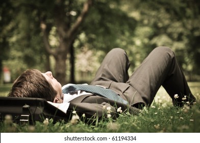 Senior People Series - Mature Business Man Lying On Grass And Relaxing In Green Park