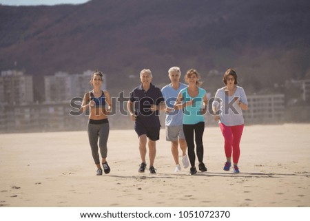 Senior people and sports coach running on sandy beach