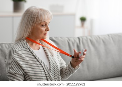 Senior People Support Concept. Portrait Of Old Woman Holding And Looking At Red Alert Button For Emergency While Staying Home Alone, Closeup, Free Copy Space. Medical Equipment For Help