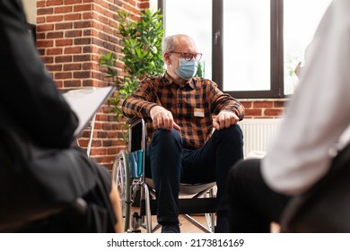 Senior Person With Disability Attending Group Therapy Session, Wearing Face Mask. Man Sitting In Wheelchair At Aa Meeting Program To Receive Counseling And Advice Against Alcohol Addiction.