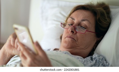Senior person in morning bed looking at phone - Shutterstock ID 2242001881