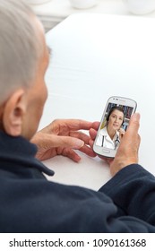 Senior Person Sitting With Her Smartphone At A Table Having A Video Call With Her Doctor, Modern Lifestyle Concept