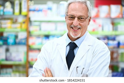 Senior Pharmacist Smiling And Folding Arms In His Store