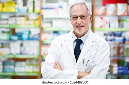 Senior Pharmacist Smiling And Folding Arms In His Store