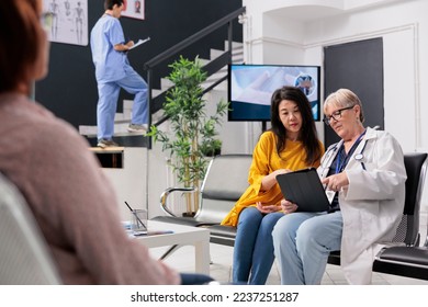 Senior physician doing examination with asian patient, taking notes on digital tablet to give prescription medicine and cure illness. Doctor and woman talking about healthcare support. - Powered by Shutterstock