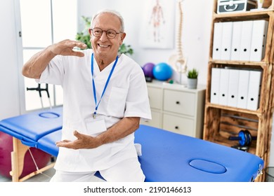 Senior physiotherapy man working at pain recovery clinic gesturing with hands showing big and large size sign, measure symbol. smiling looking at the camera. measuring concept.  - Powered by Shutterstock