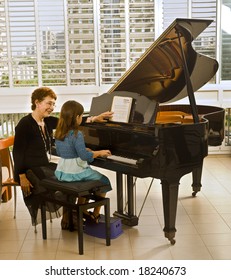 Senior Piano Teacher With Young Girl Student