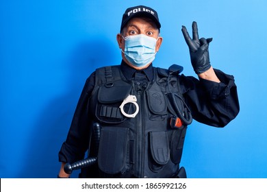 Senior Police Man Wearing Surgical Mask Smiling With Happy Face Winking At The Camera Doing Victory Sign. Number Two. 