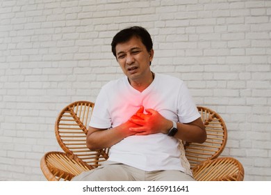 Senior portrait Asian middle-aged man with sudden cardiac disease showing pain leaky heart muscle tired and suffocating sat wooden chair in agony : Myocardial infarction (Heart Attack)
