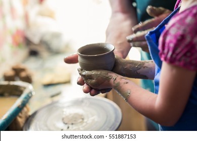 Senior Potter Teaching A Little Girl The Art Of Pottery. Child Working With Clay, Creating Ceramic Pot On Sculpting Wheel. Concept Of Mentorship, Generations. Arts Lessons, Pottery Workshop For Kids