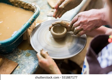 Senior Potter Teaching A Little Girl The Art Of Pottery. Child Working With Clay, Creating Ceramic Pot On Sculpting Wheel. Concept Of Mentorship, Generations. Arts Lessons, Pottery Workshop For Kids