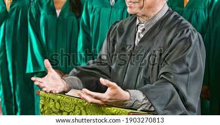 Senior preacher standing at pulpit with choir in background at church