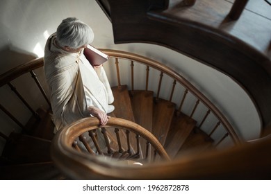 Senior Priest Holding Bible And Moving Down The Wooden Stairs