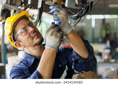 Senior professional electrical or industrial engineer inspecting and repairing a robotic system in the manufacturing factory close up. Robotic technician repairing - fixing a automated machine. - Powered by Shutterstock