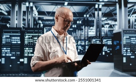 Senior professional navigating network of server machines in industrial hub. Engineer with laptop doing optimizations and checkup in high tech data center, preventing system risks
