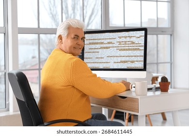 Senior programmer working at table in office