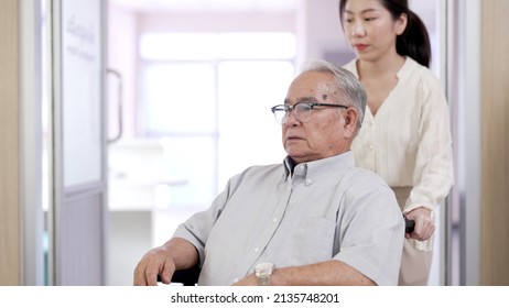 Senior Retired Man Grandpa Sitting On Wheelchair Going To The Doctor With Grandchild To Get Medical Check Up At Healthcare Center