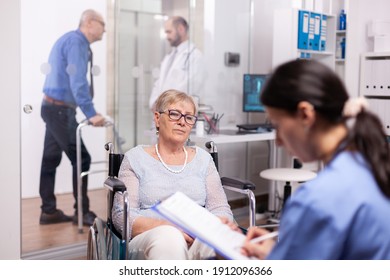 Senior Retired Patient Seeking Medical Advice And Treatment In Modern Clinic. Medical Specialist Wearing Stethoscope Discussing With Invalid Elderly Woman In Consultation Room Of Private.