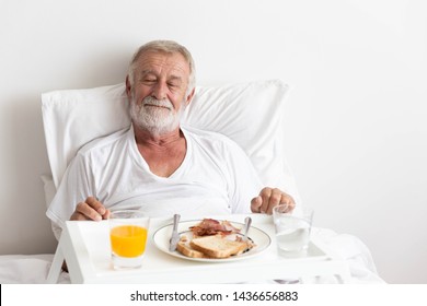 Senior retirement male has breakfast with orange juice and water on bed - Powered by Shutterstock