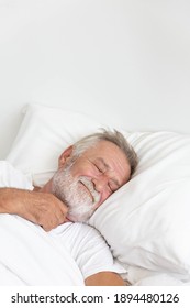 Senior retirement man sleeping happily in his white blanket bed in bedroom