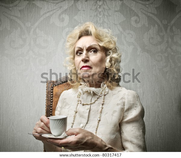 Senior rich woman having a\
cup of tea