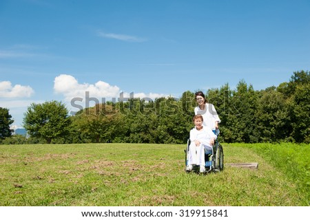 Similar – Woman carrying her mother in a wheelchair