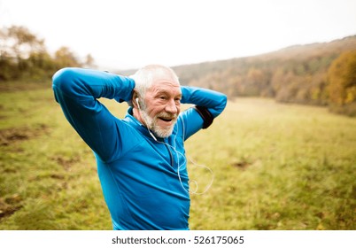 Senior runner with armband doing stretching. Autumn nature.