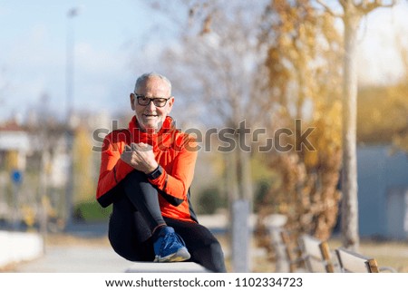 Senior runner man sitting after jogging in a park