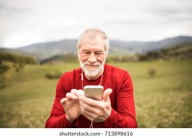 Senior runner in nature with smartphone and earphones.