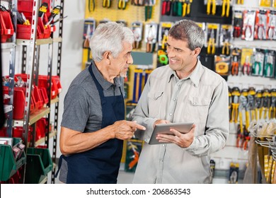 Senior Salesman With Male Customer Using Digital Tablet In Hardware Store