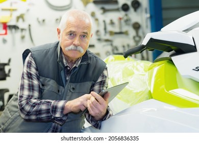 Senior Salesman Posing Next To Jet Ski In His Store