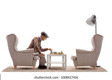 Senior seated in an armchair playing chess by himself isolated on white background