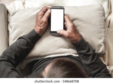 Senior Sitting On A Sofa With Mobile Phone In Hand