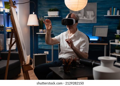 Senior Sketch Artist Using Virtual Reality Glasses Doing Air Gesture Improving Freehand Technique In Creative Workshop. Retired Art Teacher With Modern Technology Vr Goggles Looking At 3d Artwork.