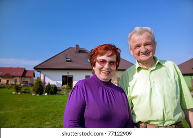 Senior Smiling Couple In Front Of Their New House