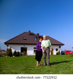 Senior Smiling Couple In Front Of Their New House