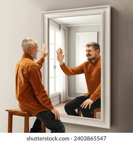 Senior smiling man looking in mirror on reflection of his younger self. Conceptual collage. Past memories. Concept of present, past and future, age, life cycle, generation, ad - Powered by Shutterstock