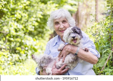 Senior Smiling Woman Hugging Her Dog In The Mountain