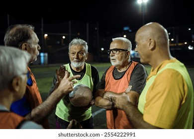 Senior soccer team discussing strategy during night game - Powered by Shutterstock