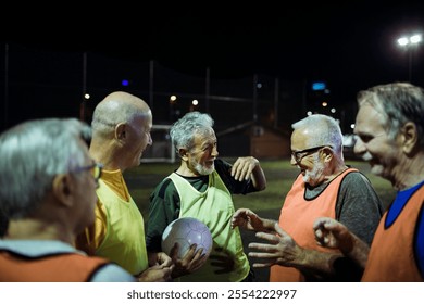 Senior soccer team discussing strategy during night game - Powered by Shutterstock