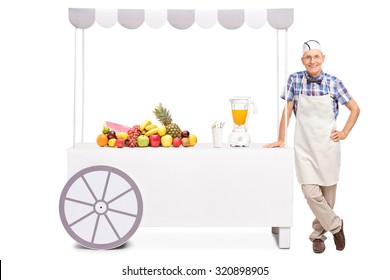 Senior Soda Jerk Standing Next To A Stall With A Juicer And A Bunch Of Fresh Fruits On It Isolated On White Background