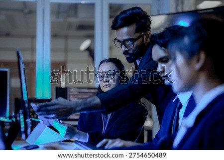 Senior software architect mentoring diverse development team on backend code. Agile scrum master leading sprint review in modern blue light tech office.