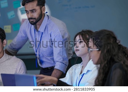 A senior software architect reviewing database schemas and machine learning code variables on a laptop display with a junior programmer.
