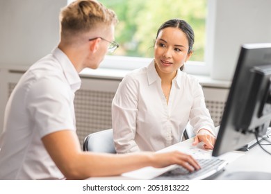 A Senior Specialist And A Junior Employee Are Sitting At The Table And Discussing Work Issues. A Man And A Woman Are Working In The Modern Office. Business, Teamwork And Problem Solving.